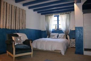 a bedroom with a bed and a chair and a window at Chambres d'Hôtes de Pesquès in Termes-dʼArmagnac