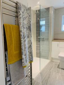 a bathroom with a shower and towels on a rack at The Barn House in Cranleigh