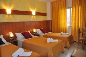 Habitación de hotel con 3 camas y cortinas amarillas en Hostal - Pensión El Amigo, en Lloret de Mar