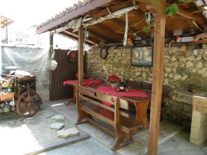un patio con una mesa y un banco en una pared de piedra en Emona Guest House, en Nesebar