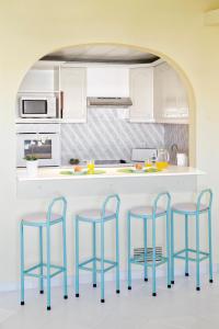 una cocina con 3 taburetes azules y una barra en Ondamar Hotel Apartamentos en Albufeira