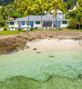 a house with palm trees on the beach at Beach Cove in Bel Ombre