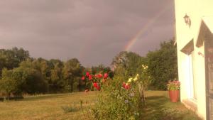 een regenboog over een veld met een huis en bloemen bij L'Autourserie in Chahaignes