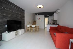 sala de estar con sofá rojo y TV en Villa La Zenia Boulevard 36, en Playa Flamenca