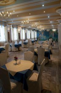 a banquet hall with white tables and chairs and chandeliers at Prezident in Dilove