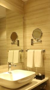 a bathroom with a sink and two mirrors and towels at Regenta Central Harsha Vapi in Vapi