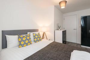 a bedroom with a large bed with yellow and white pillows at Host & Stay - Oldham Place in Liverpool