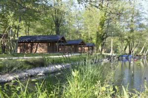 a log cabin in the woods next to a pond at Cabanes d'Aiguebelette in Saint-Alban-de-Montbel
