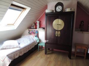 a bedroom with a bed and a clock on a dresser at Chez Jocelyne Lhermite in Bangor