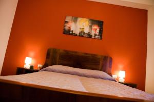 エンポリにあるLa Terrazzaのオレンジ色の壁のベッドルーム1室(ベッド1台、ランプ2つ付)