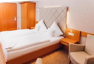 テクレンブルクにあるRinghotel Teutoburger Waldの大きなベッドと椅子が備わるホテルルームです。