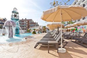 una piscina con sillas, una sombrilla y una fuente en 30º Hotels - Hotel Pineda Splash, en Pineda de Mar