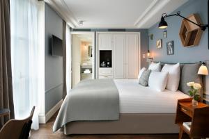 a bedroom with a large white bed and a desk at Royal Madeleine Hotel & Spa in Paris