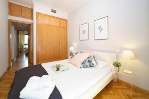 マドリードにあるApartamentos Plaza de Españaの白いベッドと木製キャビネット付きのベッドルーム1室