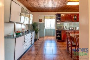 eine Küche mit Holzschränken und Fliesenboden in der Unterkunft House Rebelo in Terra Chã