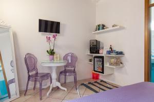 Pokój z dwoma fioletowymi krzesłami, stołem i telewizorem w obiekcie Giardino Giusti House & Court w Weronie