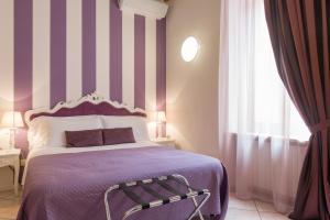 una camera con letto viola e parete a righe di Giardino Giusti House & Court a Verona