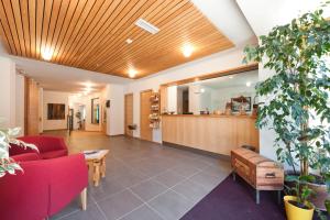 a lobby with a red couch and a table at Kreativ Hotel Landhaus Schweigl in Ultimo