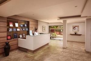 a woman standing at a counter in a lobby at The Hawaii Comforts in Panaji