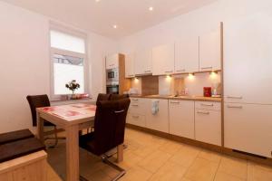 uma cozinha com armários brancos e uma mesa com cadeiras em Private Apartment em Hanôver