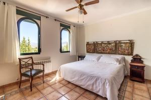 a bedroom with a bed and a chair and two windows at Villa La Piedad in Otura +44 photos
