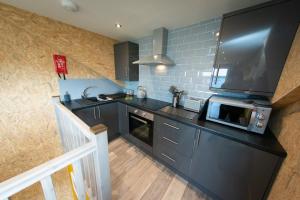 a kitchen with black cabinets and a microwave at Lochanside in Struan