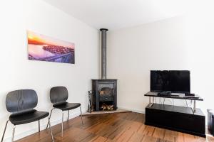 a living room with two chairs and a tv and a fireplace at Porto Gaia City House by MP in Vila Nova de Gaia