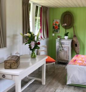 Una habitación con una mesa con un jarrón de flores. en l'Atelier au jardin d'Isabelle, en Fatouville-Grestain
