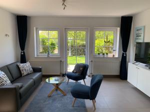 sala de estar con sofá, sillas y ventanas en Appartementanlage Lancken-Granitz en Lancken-Granitz