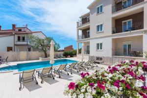 uma villa com piscina, cadeiras e flores em Apartments Villa Nina em Fažana