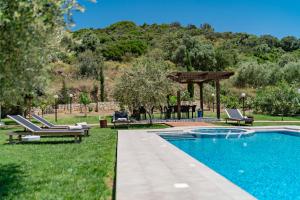 a swimming pool with lounge chairs and a gazebo at Villa Nostos in Prínos