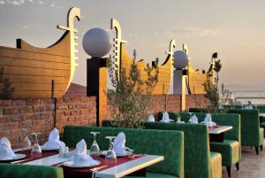 a restaurant with green chairs and tables with the ocean in the background at Ephesia Holiday Beach Club in Kuşadası