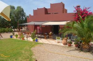 a red building with a patio with chairs and plants at Casa Naima in Ida Ougourd