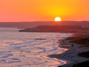 a sunset over the ocean with people walking on the beach at CA NA ROSA Son Bou in Alaior