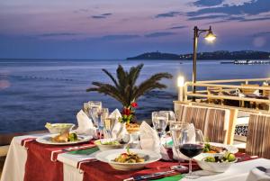 a table with plates of food and wine glasses at Ephesia Holiday Beach Club in Kuşadası