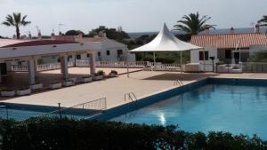 a swimming pool in a resort with a white umbrella at CA NA ROSA Son Bou in Alaior