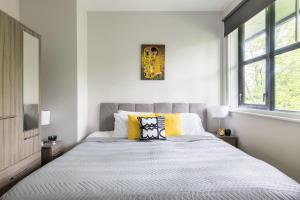 a white bedroom with a large bed with yellow pillows at homely - Watford Premier Apartments (Warner Bros Studio) in Watford