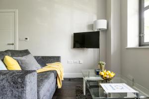 a living room with a couch and a tv at homely - Watford Premier Apartments (Warner Bros Studio) in Watford