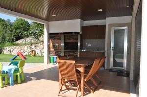 eine Küche mit einem Holztisch und Stühlen auf einer Terrasse in der Unterkunft Casa da Quinta do Sóto in Terras de Bouro