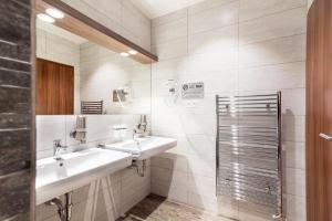 a bathroom with a sink, mirror, and shower stall at Hotel Viktor in Bratislava