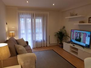 a living room with a couch and a flat screen tv at Tazones CASA AURO VUT1198AS centrico y con vistas al mar in Tazones