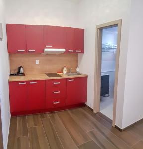 Apartment De Luna في براغ: مطبخ مع دواليب حمراء ومغسلة