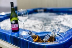 a hot tub with bottles of beer and a wine glass at City Retreat, Spacious 4 Bed House, Games Room, Parking, Hot Tub & BBQ in Cardiff