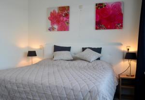 a bedroom with a white bed with two paintings on the wall at Grimaud 151 - Kustpark Village Scaldia in Hoofdplaat