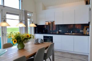 a kitchen with a wooden table and white cabinets at Grimaud 151 - Kustpark Village Scaldia in Hoofdplaat