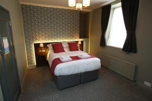 The Queens Head Hotel في روثبيري: غرفة نوم بسرير ومخدات حمراء ونافذة
