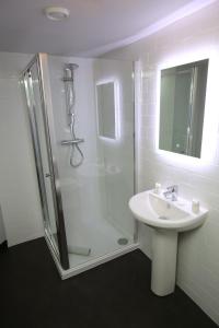 ein weißes Bad mit einer Dusche und einem Waschbecken in der Unterkunft The Queens Head Hotel in Rothbury