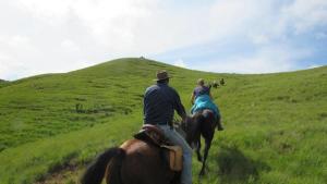 Um homem e uma mulher cavalgando num campo em MacFarlanes em Harrismith