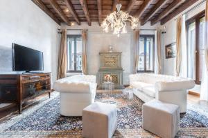 una sala de estar con muebles blancos y una lámpara de araña. en Ca' Dei Diamanti Grand Canal, en Venecia