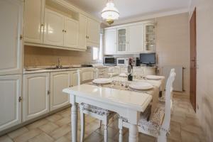 una cocina con armarios blancos y una mesa y sillas blancas. en Ginevra Apartment, en Cefalú
